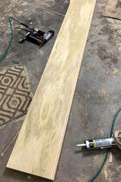 plywood topped floating shelf on the garage floor with caulk and a brad nailer
