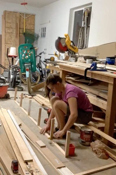 Crystel laying out 1x2 pine supports for floating shelves in the garage