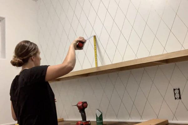 Crystel measuring for the top floating pantry shelf with a tape measure