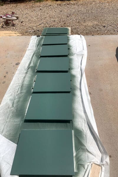 plywood pantry shelves painted green and drying on a drop cloth outside