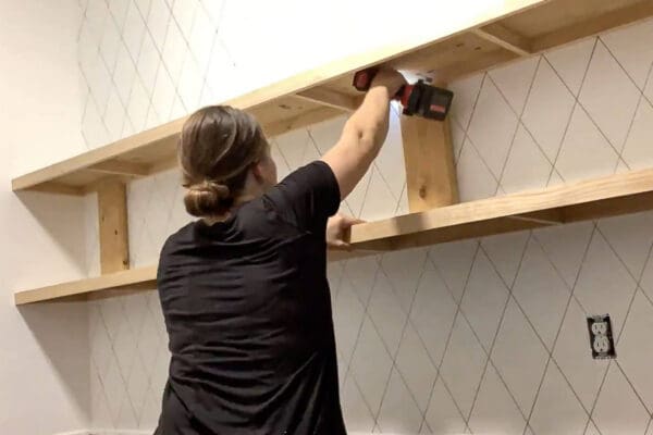 Crystel screwing the top floating pantry shelf into the wall studs