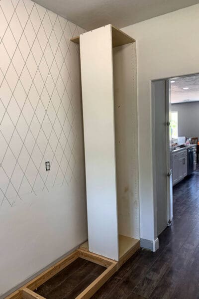 tall melamine appliance cabinet standing on its 2x4 base before the side panel