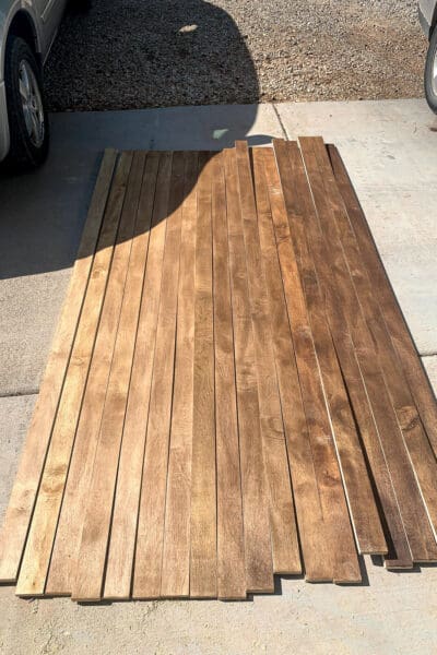 plywood strips stained in three shades of brown laid out on a driveway