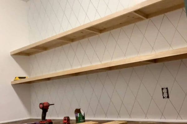 two unpainted floating pantry shelves installed above a herringbone counter
