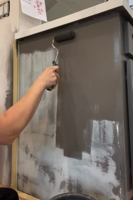 Applying paint with a roller for an affordable kitchen cabinet makeover