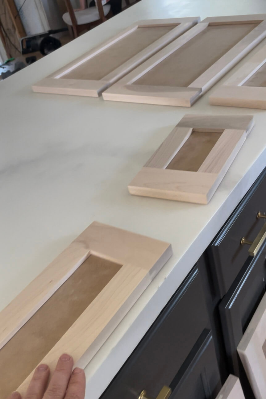 Unfinished custom cabinet doors laid out on a countertop, part of an affordable kitchen remodel project.