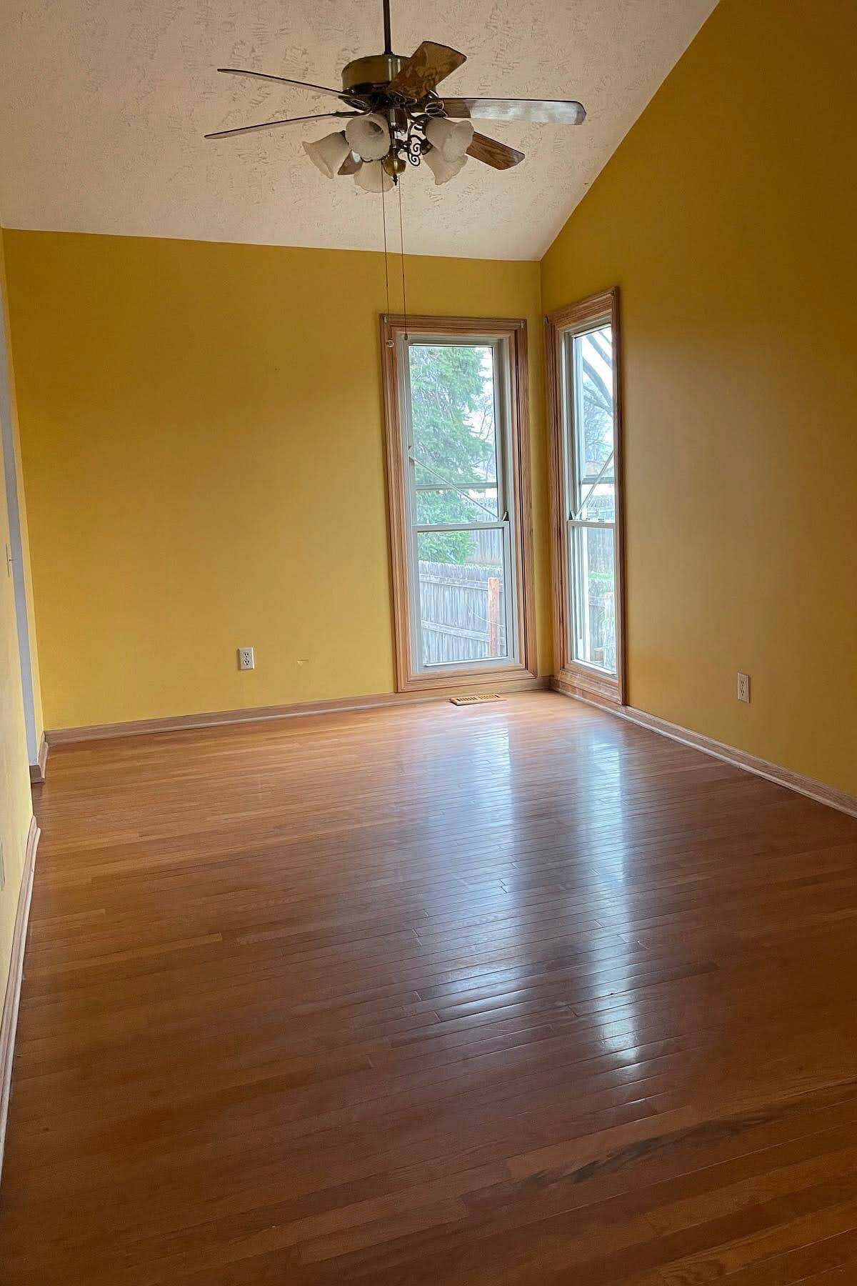 Before image of an empty room with yellow walls and wooden floors, part of an affordable kitchen remodel project.