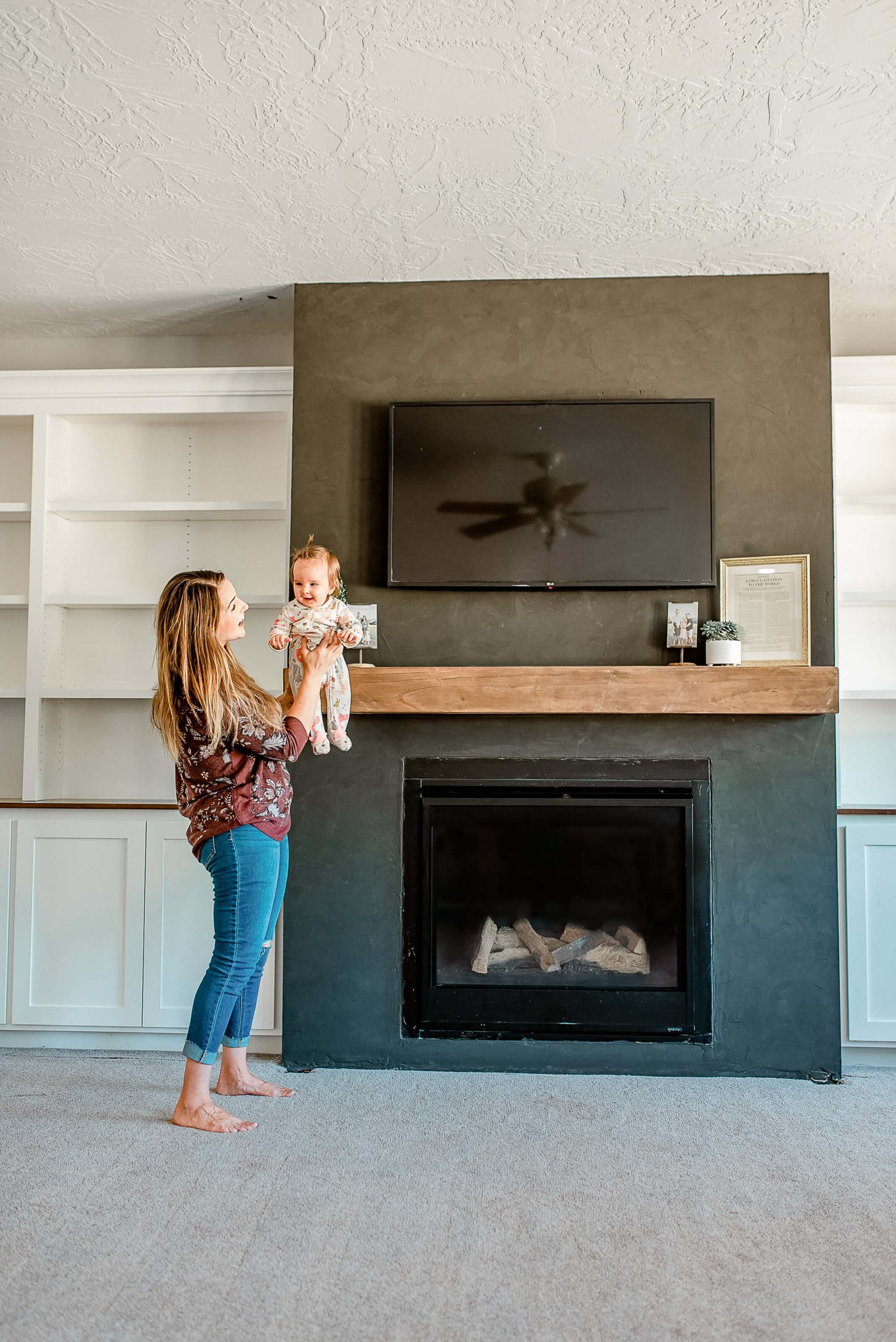 woman holding baby in front of fireplace