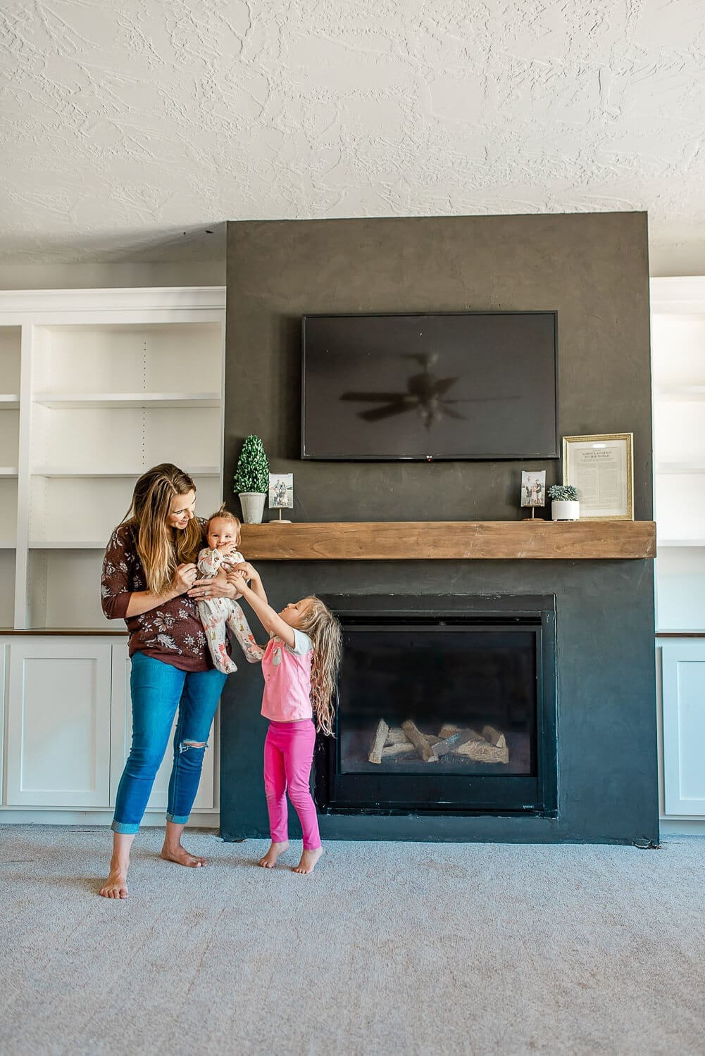 Finished DIY floating mantel installed above black fireplace with built-in shelving