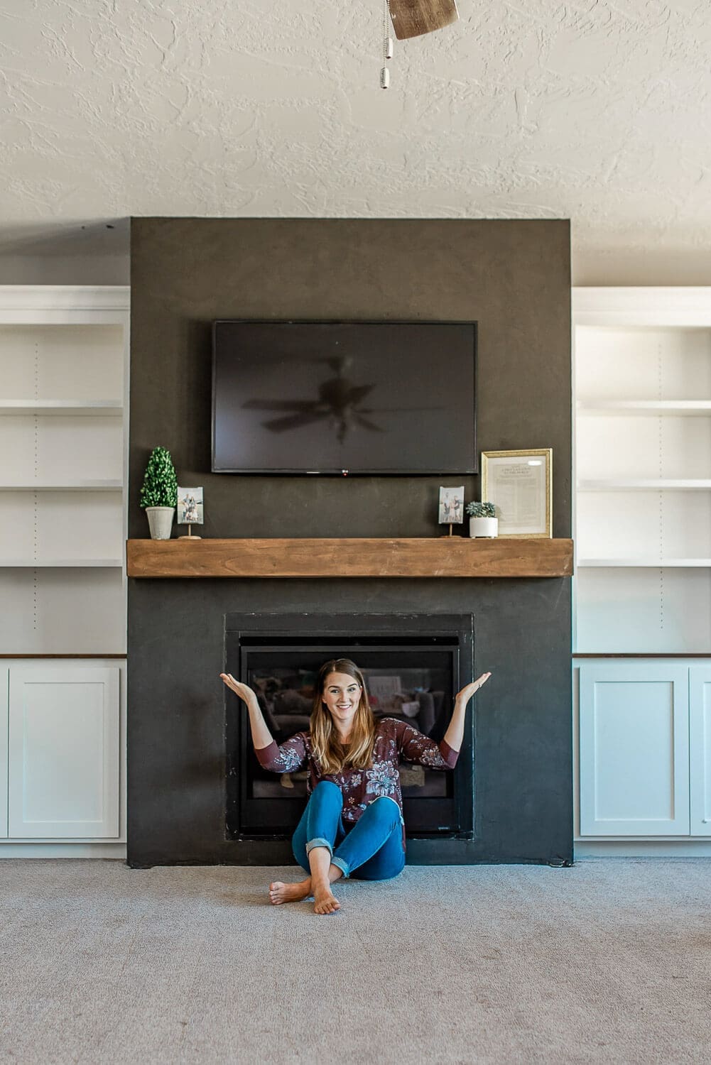 Wide view of completed fireplace with floating mantel and symmetrical white built-ins