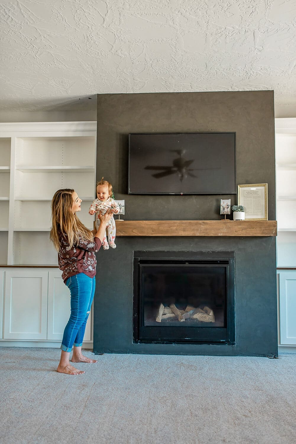 Living room showing installed floating beam mantel above modern gas fireplace