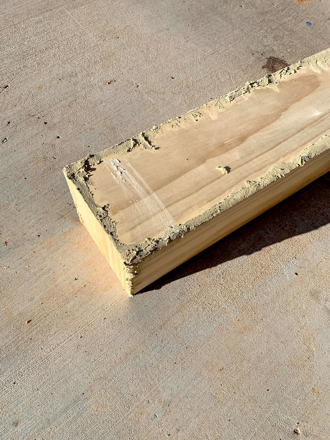 Close-up of wood filler applied along mitered edge of pine board for mantel assembly