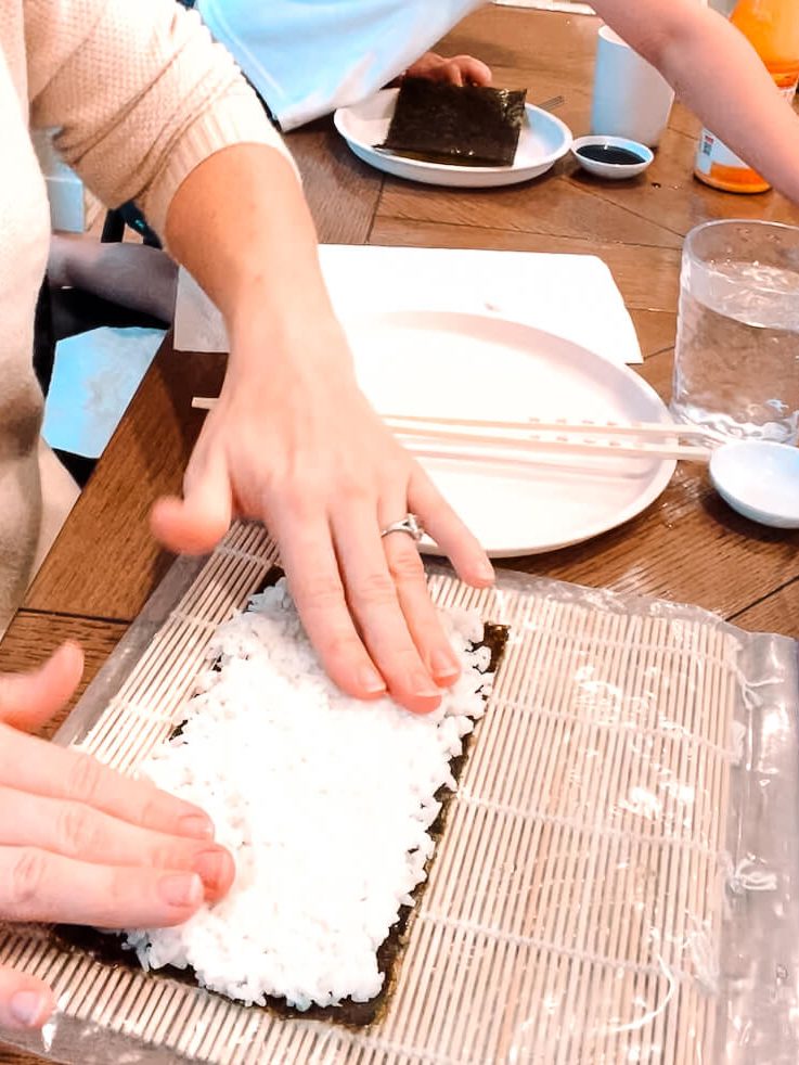 spreading rice on nori and giving tips for making sushi at home