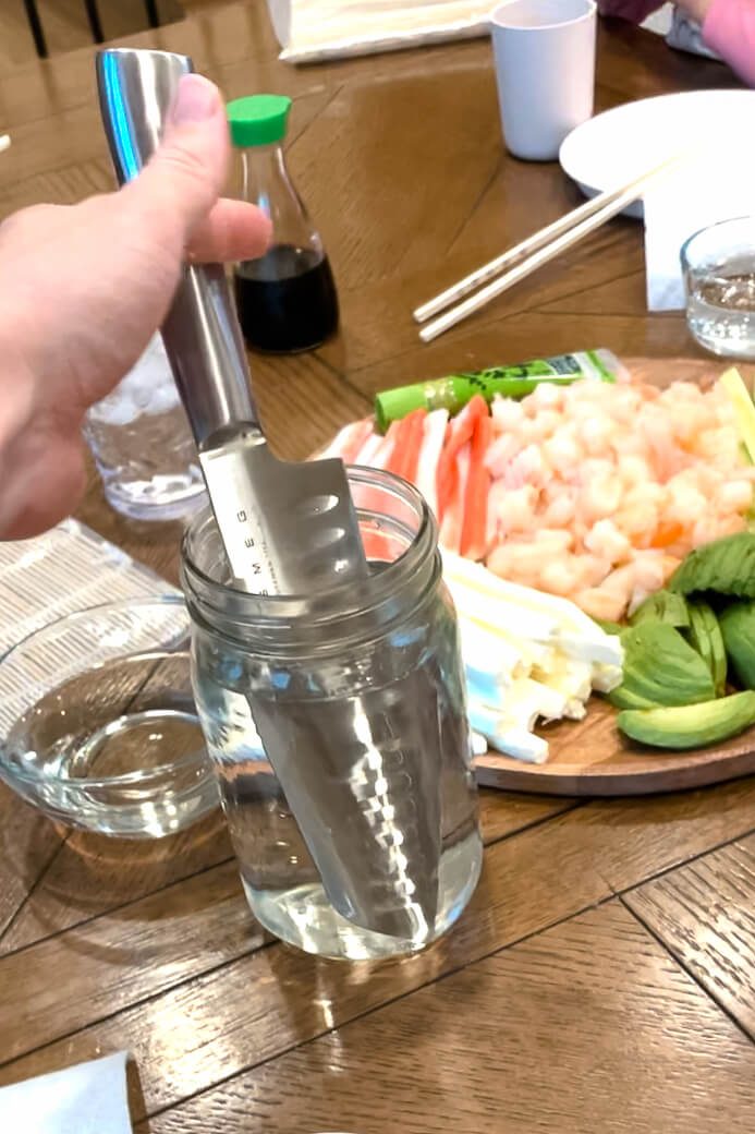 sushi knife placed in cup of water which is a tip for making sushi at home