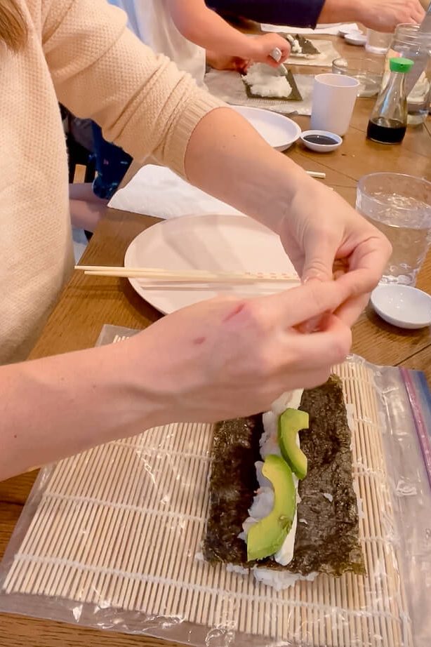 Woman making a California roll and giving tips for making sushi at home