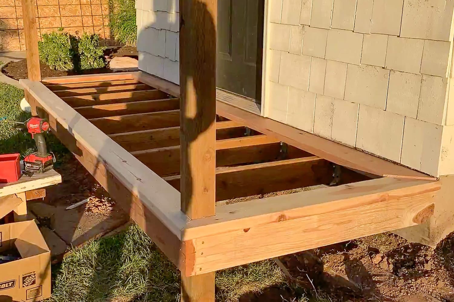 Completed redwood border trim around the porch frame with joists exposed, ready for deck boards.