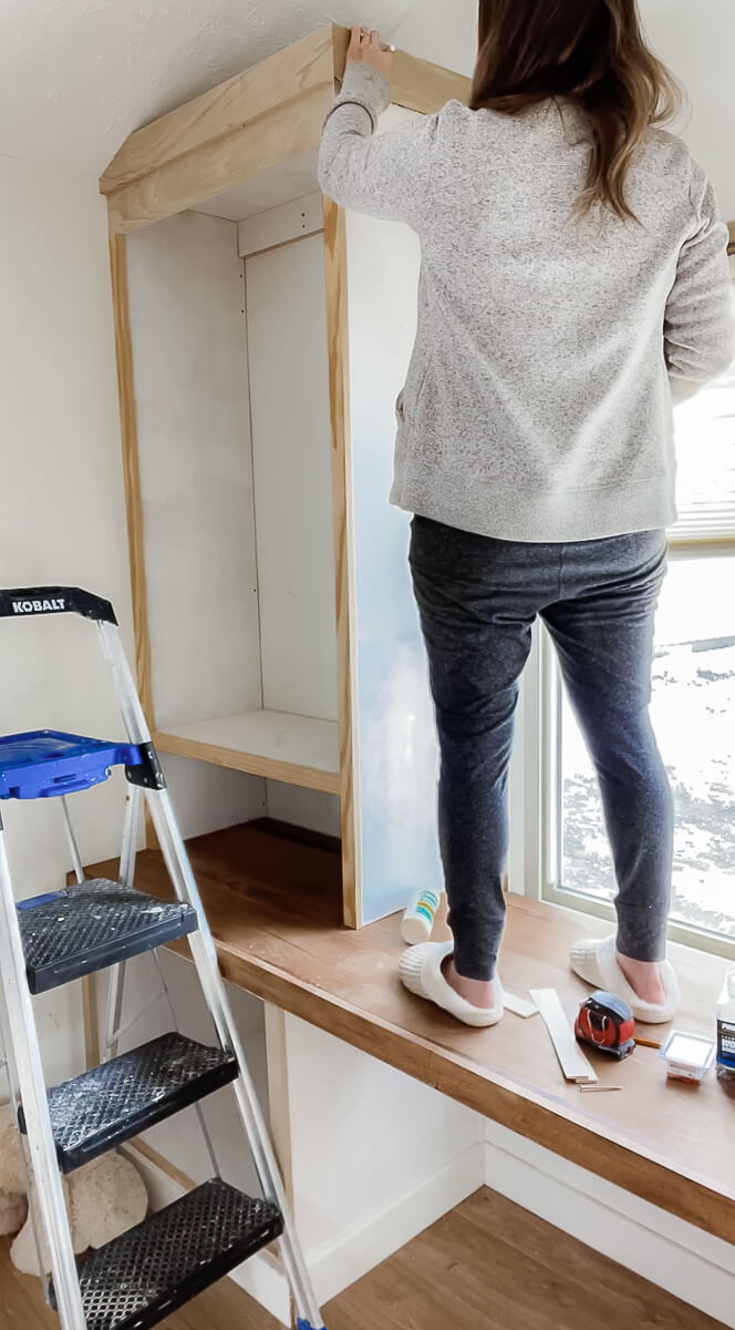 woman installing molding on a home office built in