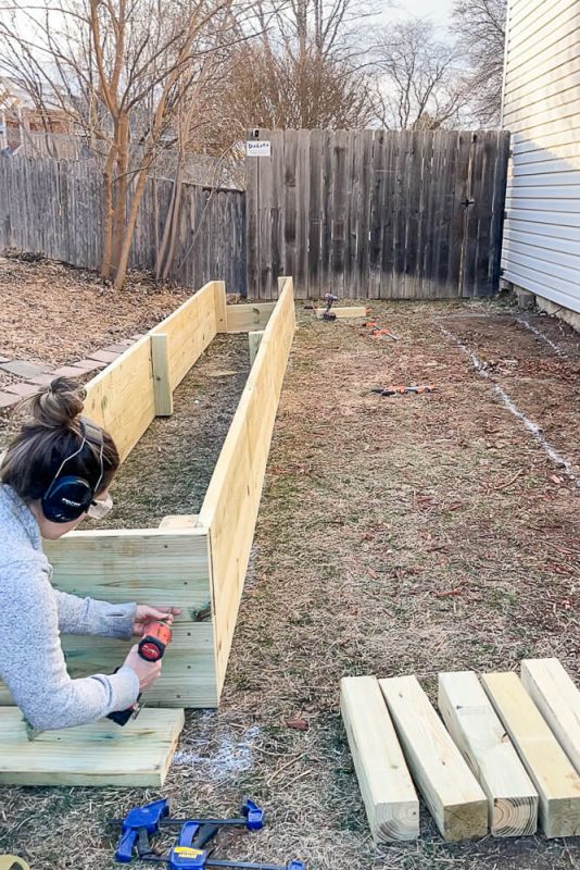 woman drilling into a raised garden bed