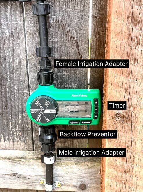 Programmable drip irrigation timer connected to hose adapter and poly tubing setup