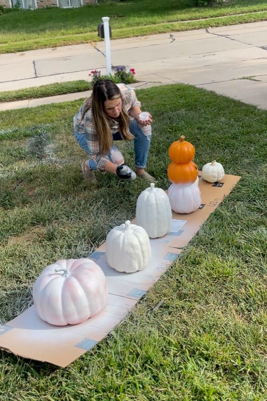 woman spray painting pumpkins