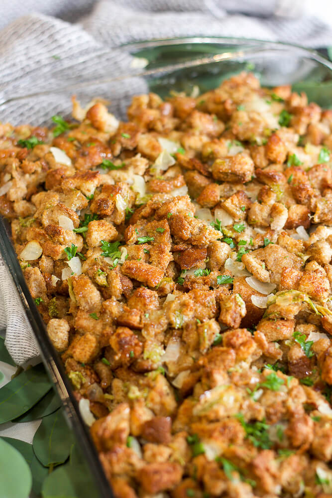 Thanksgiving stuffing baked in a glass casserole dish with golden-brown bread cubes and garnished with fresh herbs.