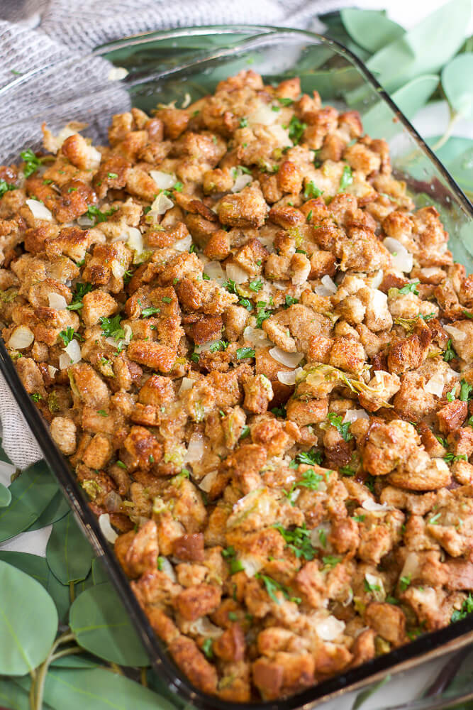 Thanksgiving stuffing baked in a glass casserole dish with golden-brown bread cubes and garnished with fresh herbs.