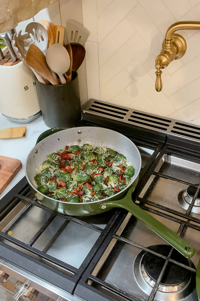 Brussels sprouts with crispy bacon and Parmesan in a green skillet on a stovetop