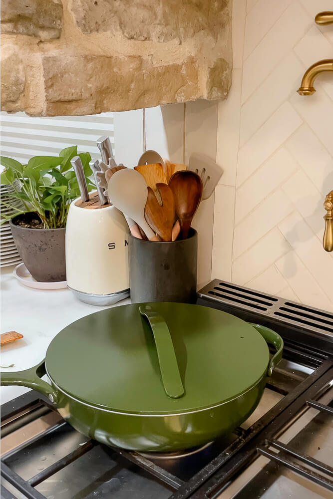 A green pan with a lid resting on the stovetop, ready to cook fresh green beans.