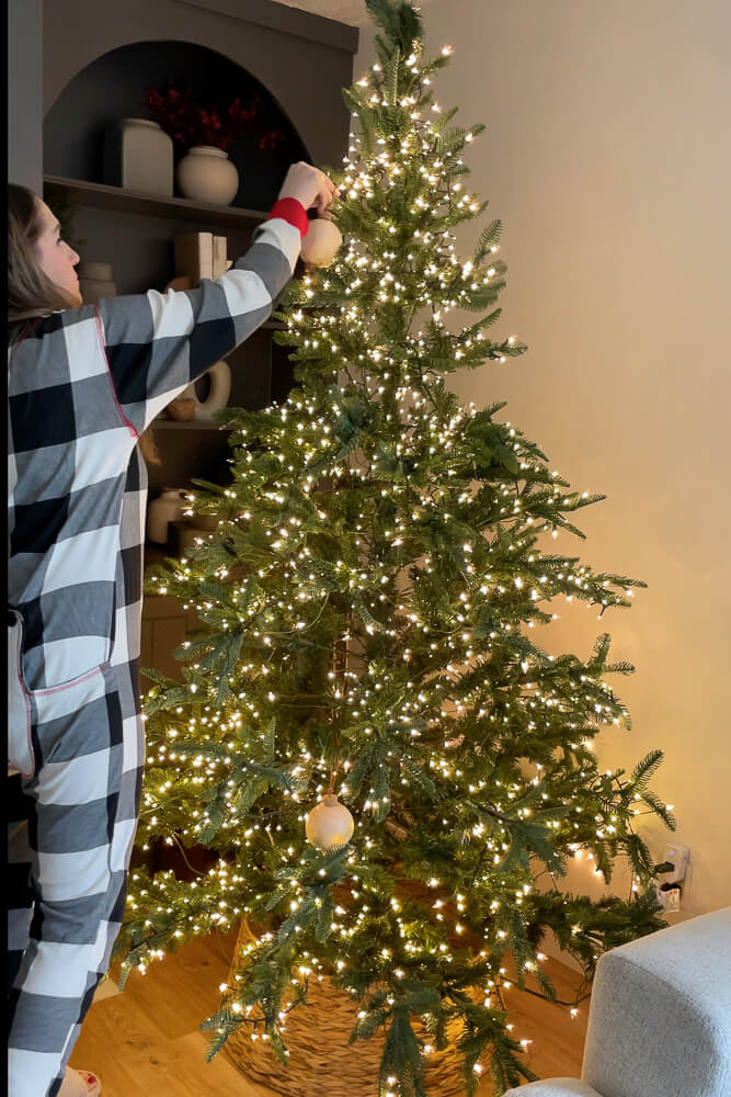 lady decorating a christmas tree in cute christmas pajamas