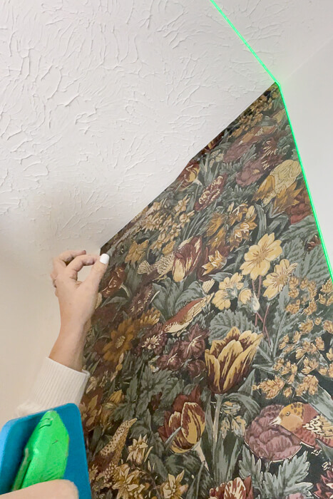 woman peeling off wallpaper