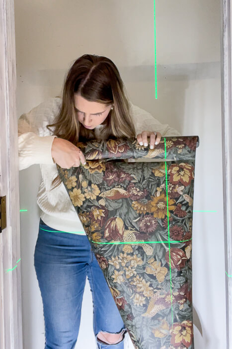 woman holding wallpaper inside a closet