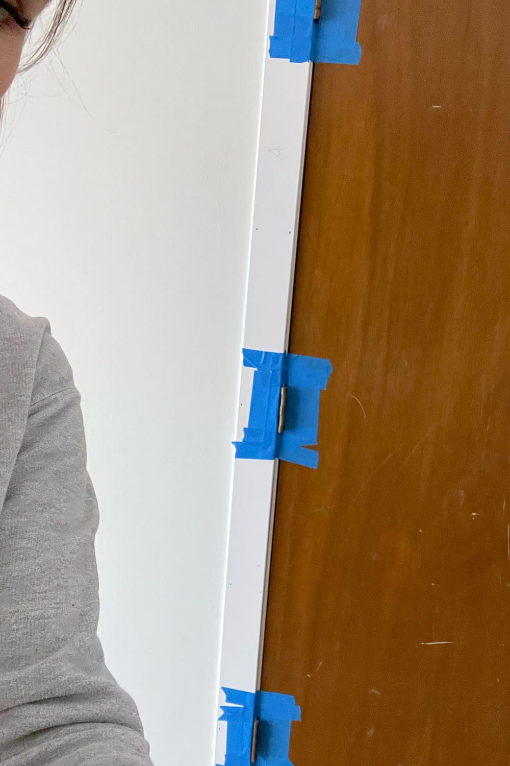 Taping trim piece to interior door with painters tape before nailing