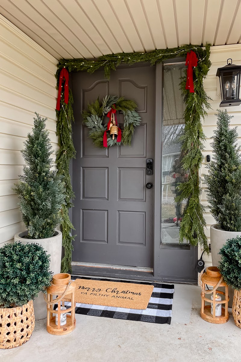 Christmas porch decor using different types of greenery and warm tones