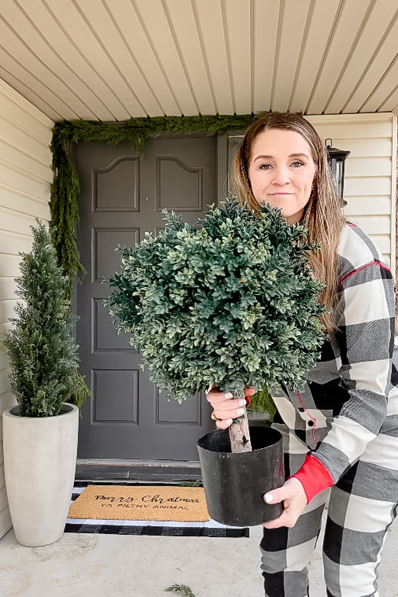Lady holding a faux boxwood plant for her front porch.