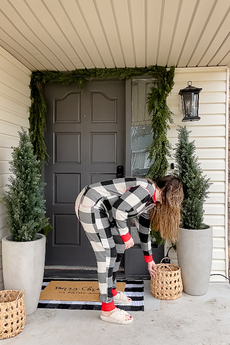 Woman placing decorative wood baskets on Christmas front porch 
