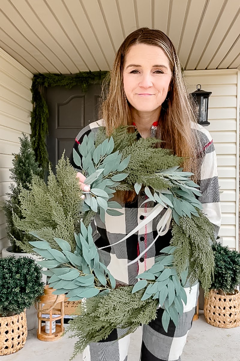 Lading holding a faux Norfolk Pine Christmas Wreath for her front door