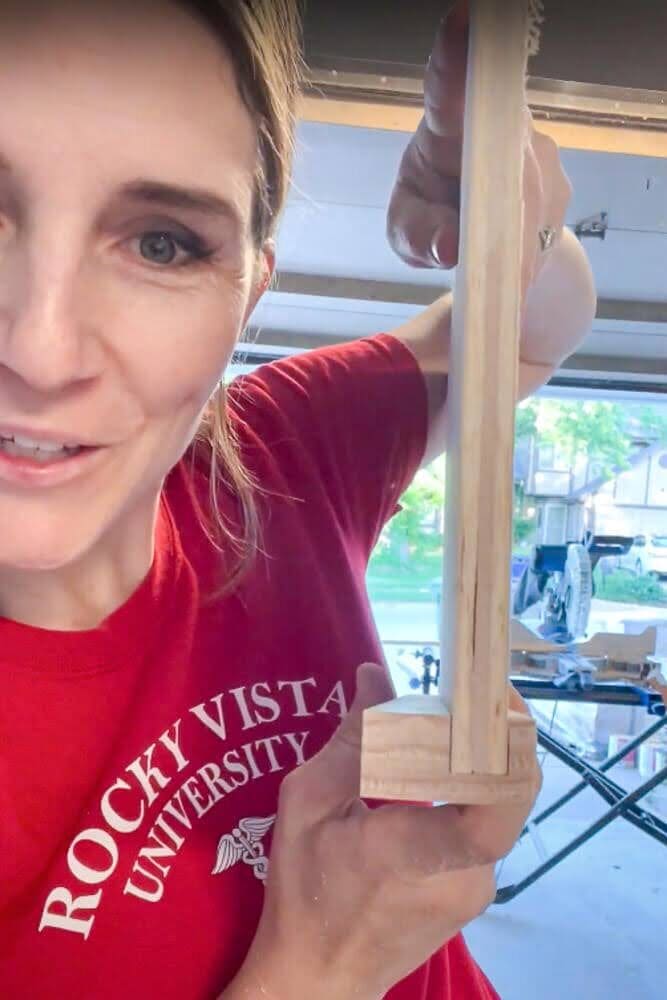 Close-up of a plywood base fitted into a routed wooden frame for a DIY pull-out shelf, showing the precise slot for a snug and sturdy fit in a kitchen cabinet.