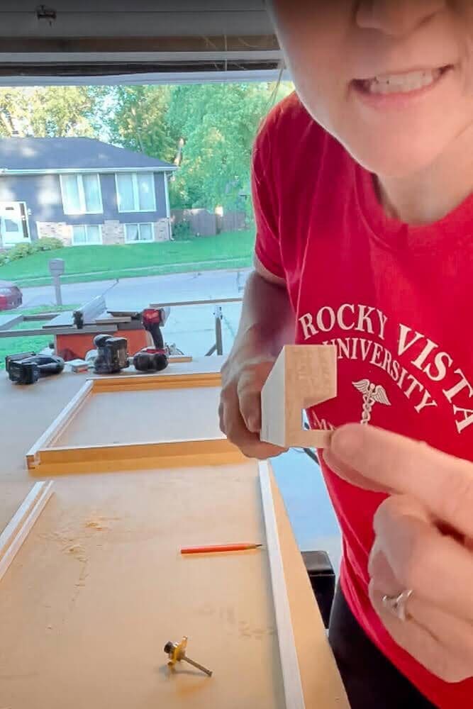Close-up of a routed wooden frame for a DIY pull-out shelf, highlighting the precisely carved groove designed to hold the plywood base securely in place