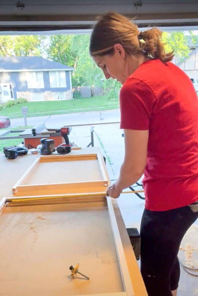 Measuring the inside of a cabinet with a tape measure to determine the correct dimensions