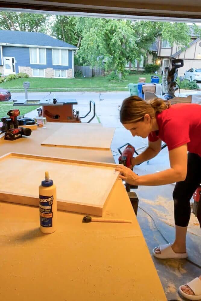 Securing the drawer frame with a brad nailer to attach the plywood bottom