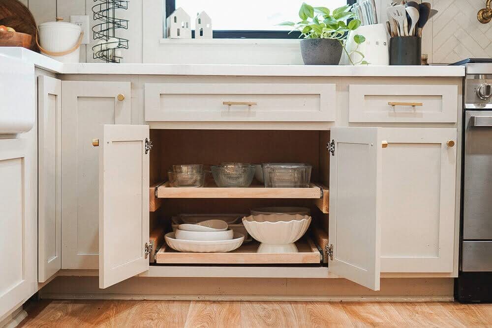 Completely finished custom pull-out shelving in kitchen cabinet with dishes inside