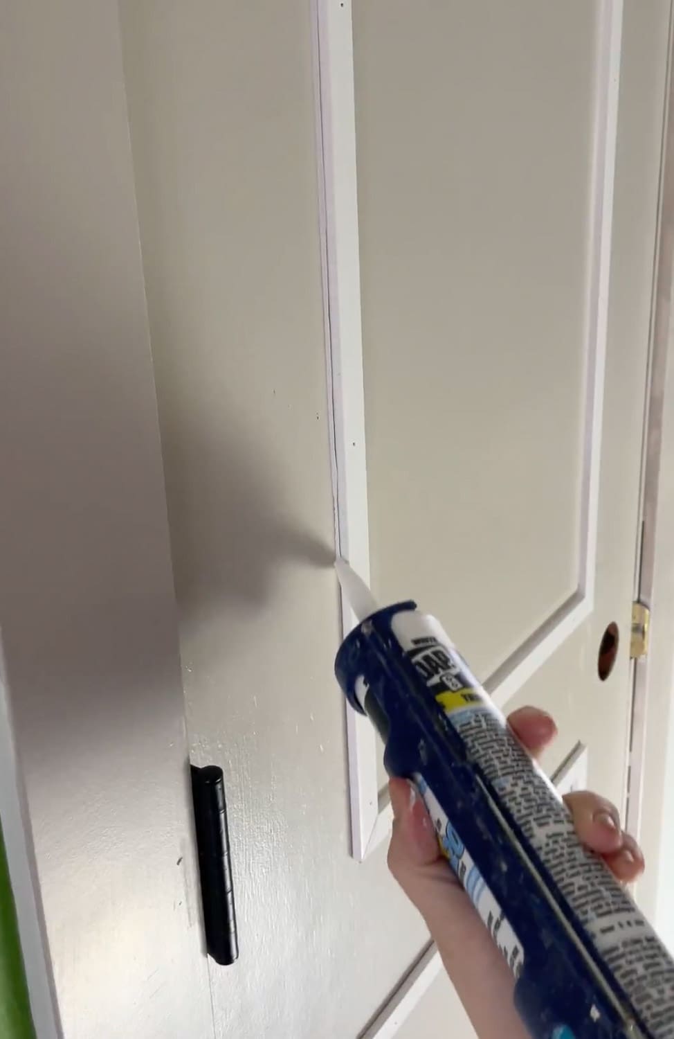 Caulking door trim seams with DAP caulk for interior door upgrade