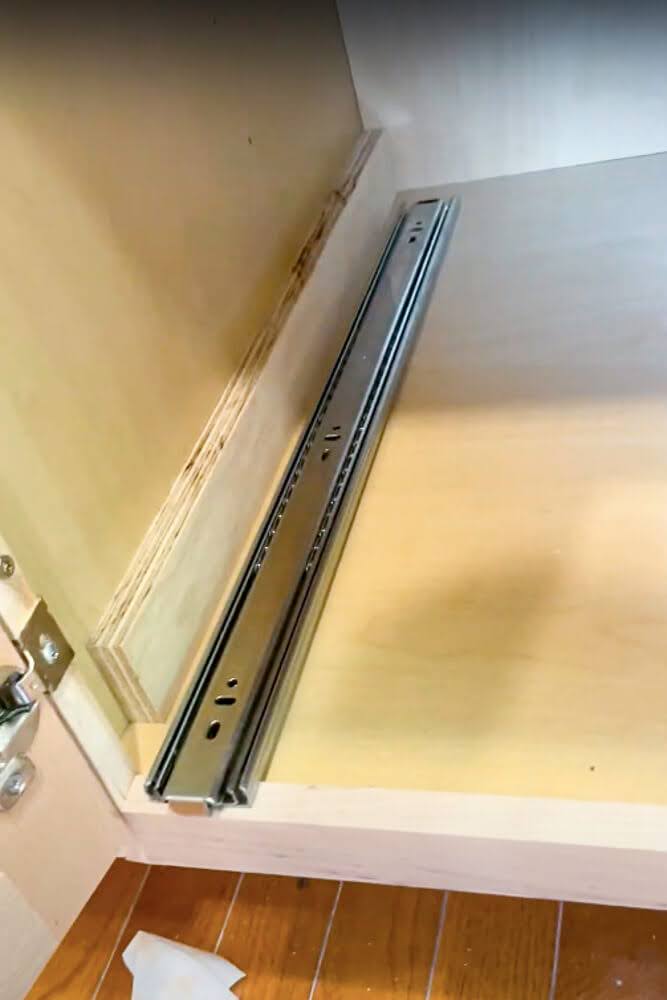 Using scrap wood to fill gap between drawer slide and side of cabinet