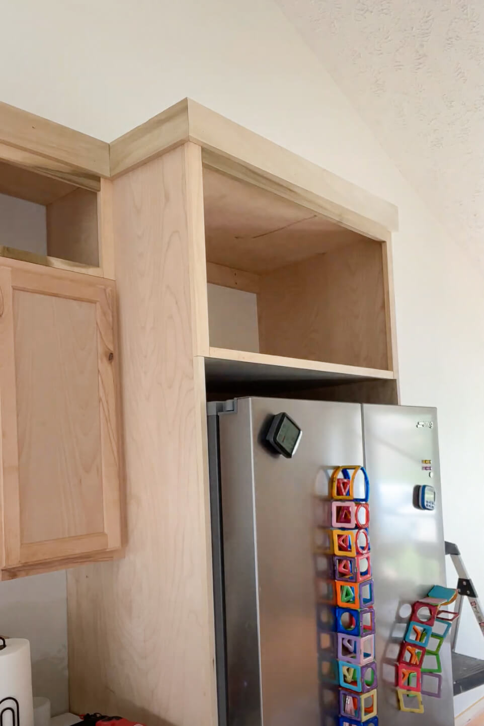 Unfinished DIY refrigerator cabinet with crown molding.