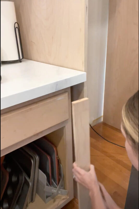 Woman filling gap between cabinets.