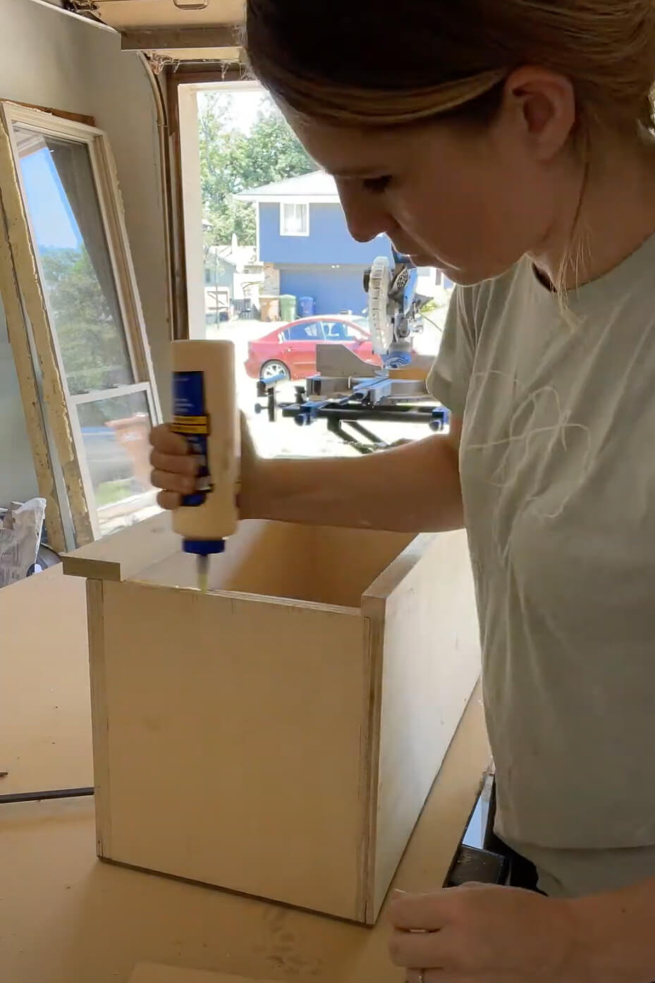 Woman using wood glue to build a kitchen cabinet.