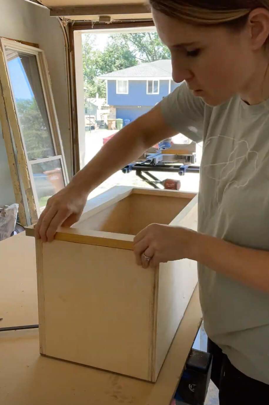 Woman adding face frame to kitchen cabinet.