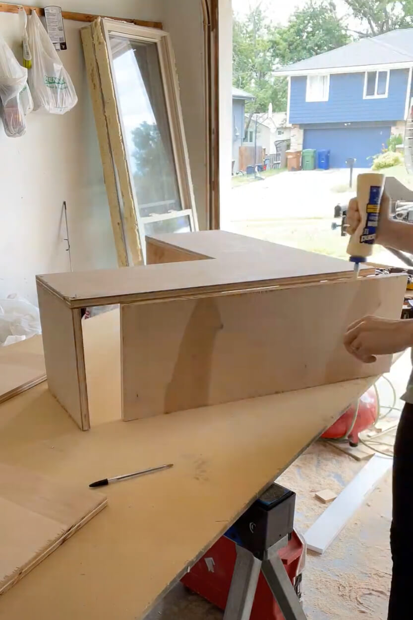 Woman using wood glue while building a kitchen cabinet.
