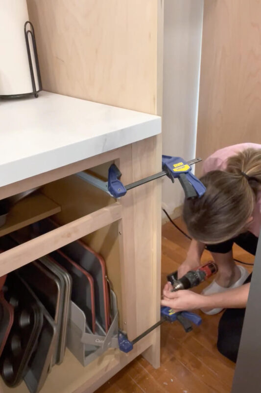 Woman installing kitchen cabinets.