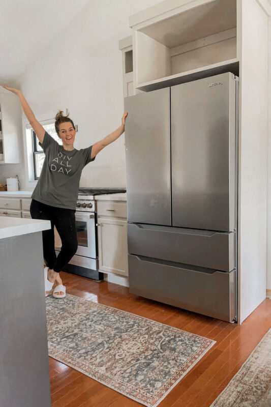 Woman showing off DIY refrigerator cabinet that she built.